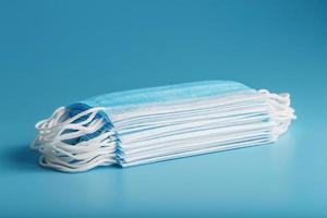 Stack of protective medical masks on a blue background, isolate. photo