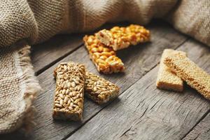 Assorted kozinaki, on old vintage background, with burlap fabric. Country style. Delicious sweets from the seeds of sunflower, sesame and peanuts, covered with shiny glaze. photo