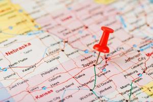 Red clerical needle on a map of USA, Kansas and the capital Topeka. Close up map of Kansas with red tack photo