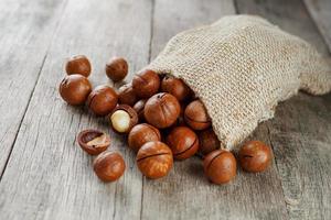 Macadamia nut on a wooden table in a bag, closeup, top view photo