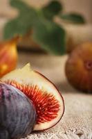 Figs on the table, group of fruits on a wooden farm table with burlap cloth. Slices of fig with pulp. Healthy and tasty fruit photo