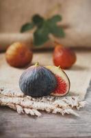 Figs on the table, group of fruits on a wooden farm table with burlap cloth. Slices of fig with pulp. Healthy and tasty fruit photo