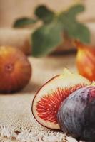 Figs on the table, group of fruits on a wooden farm table with burlap cloth. Slices of fig with pulp. Healthy and tasty fruit photo