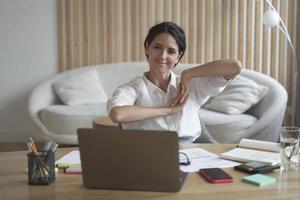 Positive business woman doing hands stretching exercises while listening to training lectures online photo
