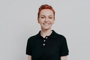 Young happy gorgeous redhead woman smiling at camera while posing isolated over grey background photo