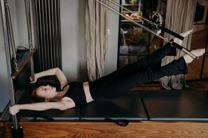 mujer joven trabajando duro en el reformador de pilates foto