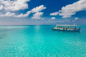 Wonderful Maldivian boat Dhoni on tropical blue sea, taking tourist to snorkeling and diving to see underwater wildlife. Landscape of beach and coast with view of seascape photo