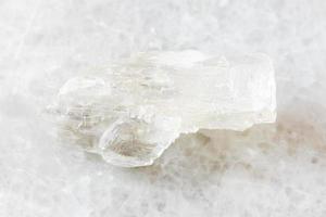 roca petalita sin pulir sobre mármol blanco foto