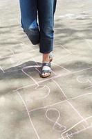 girl hoping in hopscotch outdoors photo