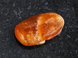 polished Spessartine gemstone on dark photo