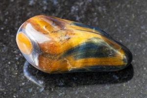 tumbled tiger-eye and hawk-eye gemstone on dark photo