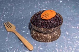 Healthy food black rice in coconut bowl has carrot. photo