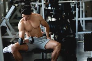 Young man workout, lifting with dumbbell to build muscle in fitness at gym. photo