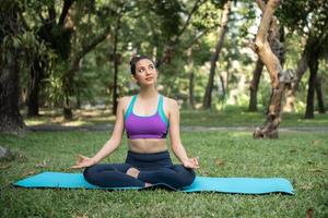 joven mujer sana asiática haciendo meditación de yoga en el parque. foto