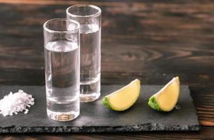 Glasses of tequila with lime wedges photo