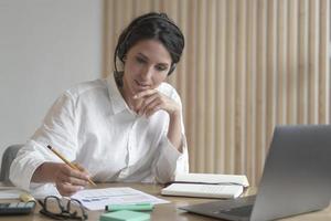 joven consultora de negocios profesional en auriculares hablando con el cliente en línea en la oficina foto