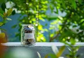 Coins in glass bottles on nature background. The concept of savings and investment. photo