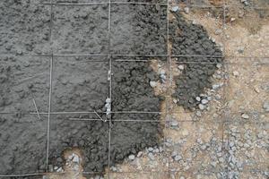 vista anterior del fondo de la construcción. cemento mezclado con piedra se vierte sobre el suelo con una estructura de rejilla de acero. foto