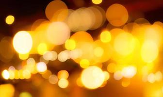 Blur gold color bokeh background. Blur abstract background of city light. Warm light with beautiful pattern of round bokeh. Orange festive light in the night. Street flare lights in the city at night. photo
