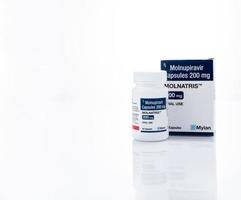 CHONBURI, THAILAND-OCTOBER 17, 2022 Molnupiravir capsules 200 mg in drug bottle and paper box packaging for treatment covid-19. Molnatris manufactured by Mylan Laboratories under license from Merck photo