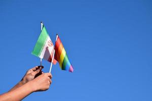 Iran flag and rainbow flag, LGBT symbol, holding in hands, bluesky background, concept for LGBT celebration in Iran and around the world in pride month, June, soft and selective focus, copy space. photo