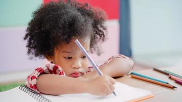 African kids drawing and do homework in classroom, young girl happy funny study and play painting on paper at elementary school. Kid drawing and painting at school concept. photo