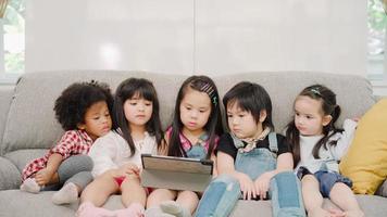 grupo de niños que usan tabletas en el aula, niños y niñas multiétnicos felices usando tecnología para estudiar y jugar en la escuela primaria. los niños usan la tecnología para el concepto de educación. foto