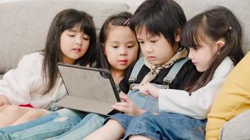 grupo de niños que usan tabletas en el aula, niños y niñas multiétnicos felices usando tecnología para estudiar y jugar en la escuela primaria. los niños usan la tecnología para el concepto de educación. foto