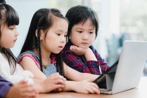 Group of children using laptop in classroom, Multi-ethnic young boys and girls happy using technology for study at elementary school. Kids use technology for education concept. photo