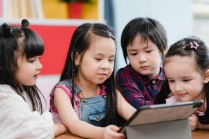 Group of children using tablet in classroom, Multi-ethnic young boys and girls happy using technology for study and play games at elementary school. Kids use technology for education concept. photo