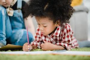 African kids drawing and do homework in classroom, young girl happy funny study and play painting on paper at elementary school. Kid drawing and painting at school concept. photo