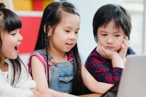 Group of children using laptop in classroom, Multi-ethnic young boys and girls happy using technology for study at elementary school. Kids use technology for education concept. photo