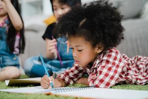 African kids drawing and do homework in classroom, young girl happy funny study and play painting on paper at elementary school. Kid drawing and painting at school concept. photo