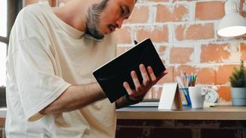Freelance Asia guy working at his desk in office taking a call on his mobile phone while writing notes on a notepad. Working from home, remotely work, social distancing, quarantine for coronavirus. photo