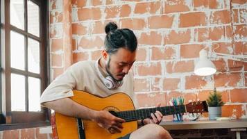 Artists producing music in their home sound studio, Asian man playing guitar and singing in living room at home. Lifestyle man relax in morning at home concept. photo