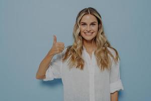Cheerful blonde girl showing thumbs up gesture photo