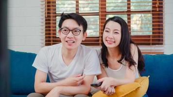 Asian couple watching television in living room at home, sweet couple enjoy love moment while lying on the sofa when relaxed at home. Lifestyle couple relax at home concept. photo