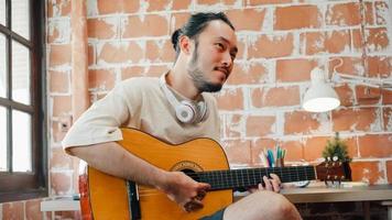 Artists producing music in their home sound studio, Asian man playing guitar and singing in living room at home. Lifestyle man relax in morning at home concept. photo