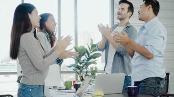 Group of cheerful happy Asian creative business women and men enjoy and having fun dancing while working in her office. Group of casually dressed business people discussing ideas in the office. photo