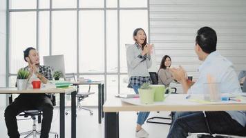 Group of cheerful happy Asian creative business women and men enjoy and having fun dancing while working in her office. Group of casually dressed business people discussing ideas in the office. photo
