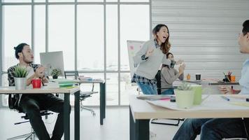 Group of cheerful happy Asian creative business women and men enjoy and having fun dancing while working in her office. Group of casually dressed business people discussing ideas in the office. photo