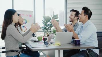 Group of cheerful happy Asian creative business women and men enjoy and having fun dancing while working in her office. Group of casually dressed business people discussing ideas in the office. photo