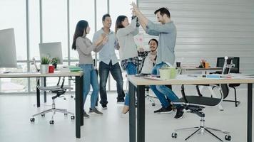 Group of cheerful happy Asian creative business women and men enjoy and having fun dancing while working in her office. Group of casually dressed business people discussing ideas in the office. photo