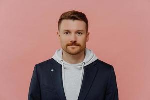 Portrait of confident ginger man on dusty rose background photo