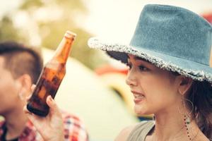 Group of man and woman enjoy camping picnic. Young mixed race Asian woman and man. Young people's hands toasting and cheering beer. Vintage filtered image photo