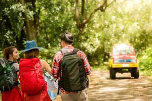 Hiking - hikers looking at map. Couple or friends navigating together smiling happy during camping travel hike outdoors in forest. Young mixed race Asian woman and man. photo