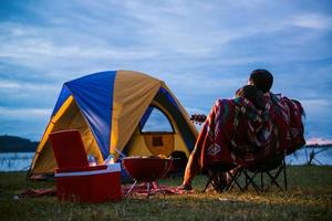 Tent carefree couple relaxing remote travel concept - Romantic asian couple tourists sitting at a campfire near tent, hugging each other under trees and night sky. Night camping photo