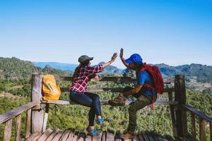 Asian couple Tourists with backpacks Happy to travel She raised her hand to make a heart shape and enjoy the natural scenery on the mountain. photo