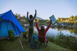 Campamento de pareja asiática en la montaña en la aldea superior cerca del lago, concepto de viaje de campamento, mapa conceptual de viaje y relajación. foto