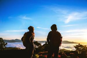 amantes de las mujeres y los hombres asiáticos viajan relajarse en las vacaciones. ponerse de pie para el amanecer en la montaña foto